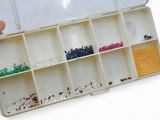 une personne tenant une boîte contenant des perles de différentes couleurs