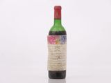 une vieille bouteille de vin posée sur une surface blanche