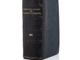 an old black book sitting on top of a white surface