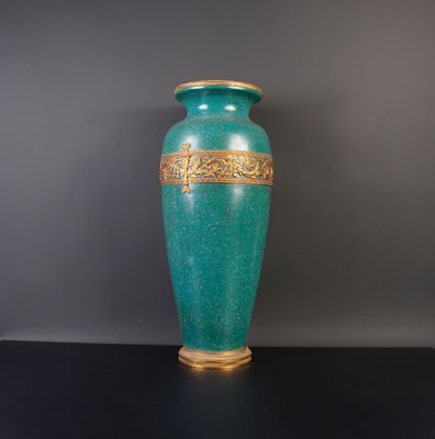 un vase vert orné d'une bordure dorée, posé sur une table noire