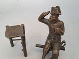 a bronze statue of a man sitting on a bench next to a chair
