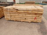 several pieces of wood are stacked on pallets in a parking lot