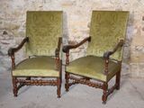 pair of green upholstered chairs in front of a stone wall