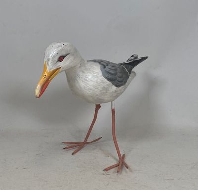un oiseau qui se tient au sol, le bec ouvert