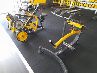 une salle de sport équipée d'une rangée de vélos d'appartement et d'haltères