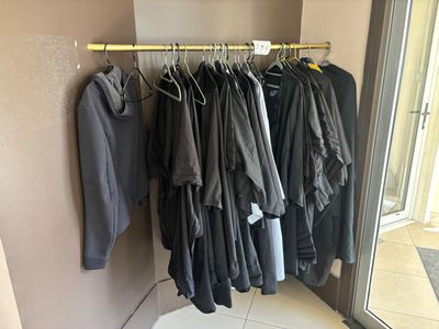 beaucoup de vêtements suspendus à une étagère dans une pièce