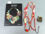 un livre et un collier posés sur une table à côté d'un livre