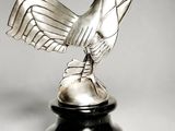 an image of a silver rooster statue on a black pedestal