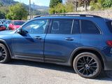 a blue mercedes suv parked on the side of the road