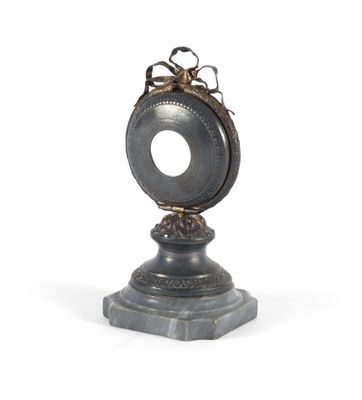 une horloge en argent posée sur un socle, sur fond blanc