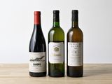 three bottles of wine are lined up on a wooden table