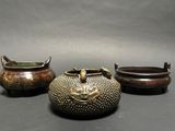 three bronze pots with handles and handles sitting next to each other
