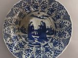 a blue and white plate with a picture of people on it