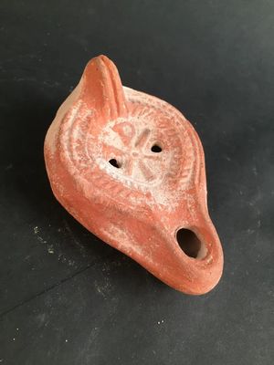 an old red clay animal head with a hole in the middle