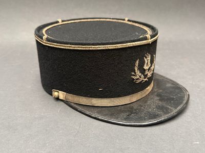 une image représentant un chapeau noir orné d'un emblème doré
