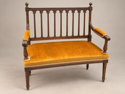 un vieux banc en bois dont l'assise est recouverte de velours jaune