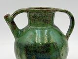 a green vase that is sitting on a white surface
