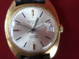 a gold wrist watch with a white dial on a black leather strap