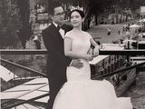bride and groom posing for a photo on a bridge near a river
