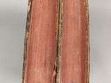 two old books are sitting on top of each other on a table