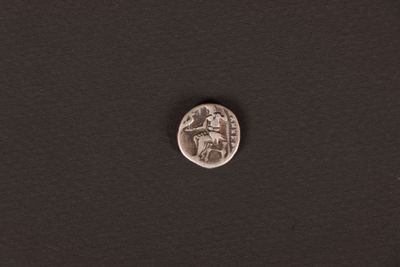a silver coin on a black surface with a white background