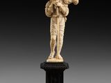 une figurine en ivoire sculpté représentant un homme tenant une flûte