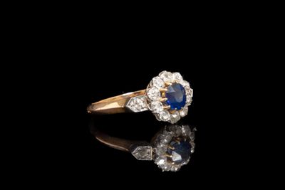 un gros plan d'une bague sertie d'un diamant et d'un saphir sur une surface noire