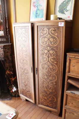une armoire dans un coin d'une pièce où sont accrochées des photos au mur