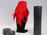 a red feathered hat and a green vase on a white table