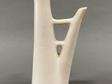 a white vase with a wooden handle sitting on top of a table