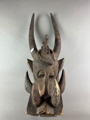 une image représentant un masque en bois muni de cornes sur fond blanc