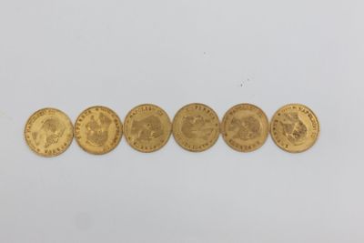 une rangée de cinq pièces d'or posées sur une surface blanche