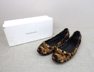 ballerines à imprimé léopard ornées de clous dorés sur le devant d'une boîte blanche