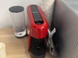 une cafetière rouge posée sur un plan de travail, à côté d'un mixeur