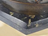 a bronze statue of a man sitting on top of a table