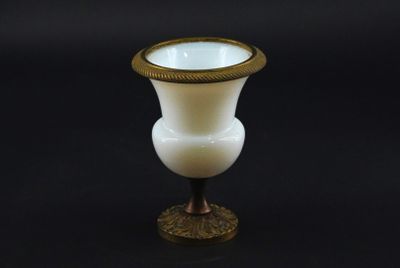 a white vase with a gold rim sitting on a black surface