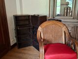 une chaise en osier avec un coussin rouge, dans un coin de la pièce