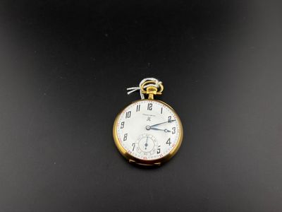 une petite montre de poche en or posée sur une surface noire