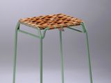 une image représentant un tabouret vert avec une assise tressée