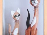 two wooden cats sitting next to each other on a shelf