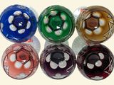 six glass balls with different colors of marbles on a white surface