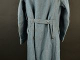 an old blue coat on a mannequin stand against a black background