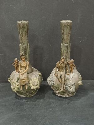 two vases that have statues on them on a table