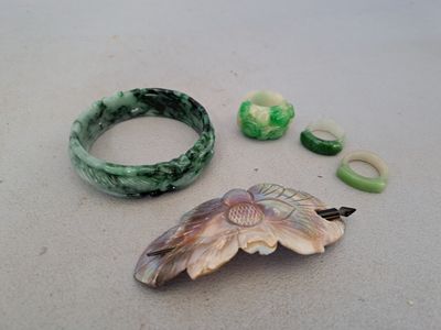 two pieces of jewelry sitting on a table next to each other