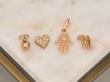 three gold - plated charms on a marble surface in a gold frame