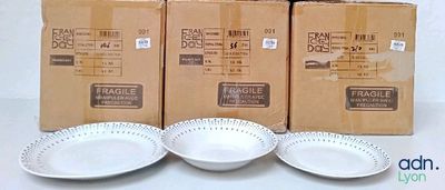 trois assiettes blanches et deux bols blancs sont posés sur une table, à côté d'une boîte de nourriture