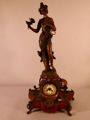 une statue représentant une femme tenant un oiseau à côté d'une horloge