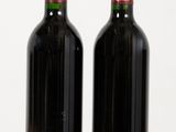 two bottles of wine sitting on top of a wooden table next to each other
