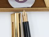 the pen is next to a box with a gold pen and a black pen
