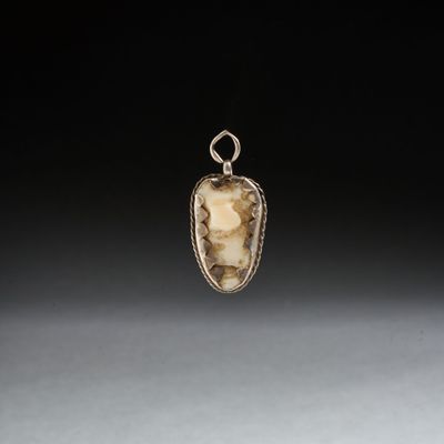 une image représentant un pendentif orné d'une pierre en forme de visage